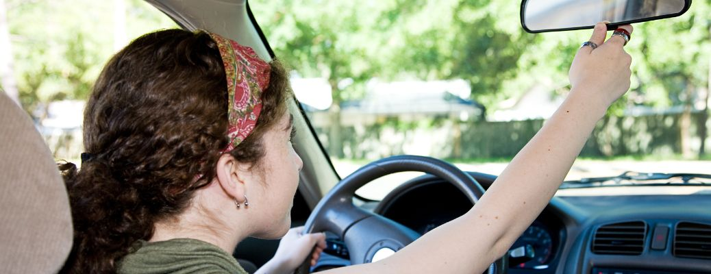 a young girl adjusting the rearview mirror