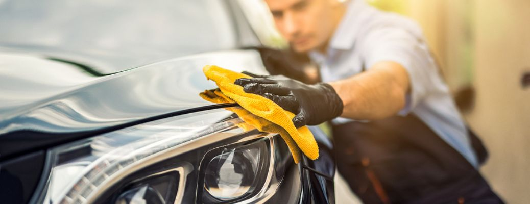 a technician cleaning the headlight of a car