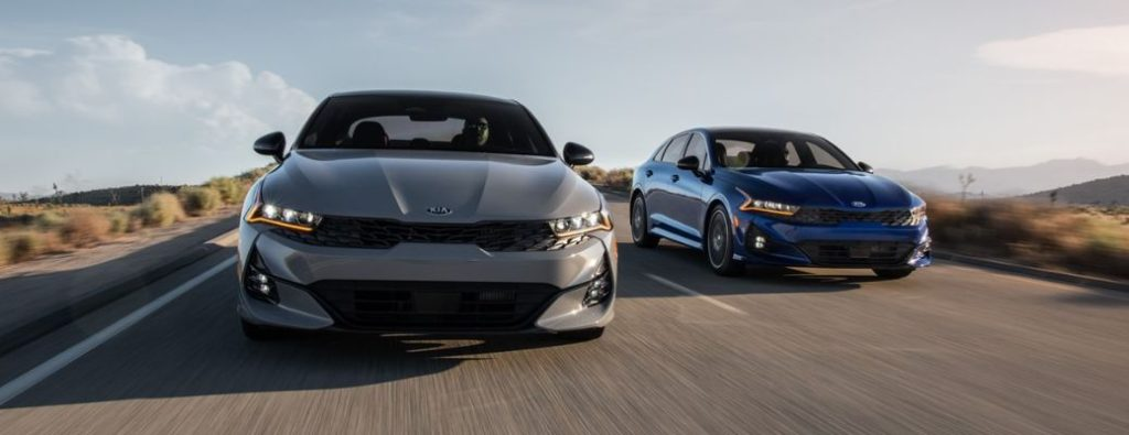 Front view of a 2021 Kia K5 models speeding on a road