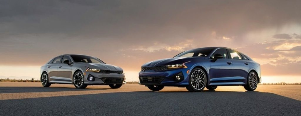 Two 2024 Kia K5 models backdropped by the evening sky