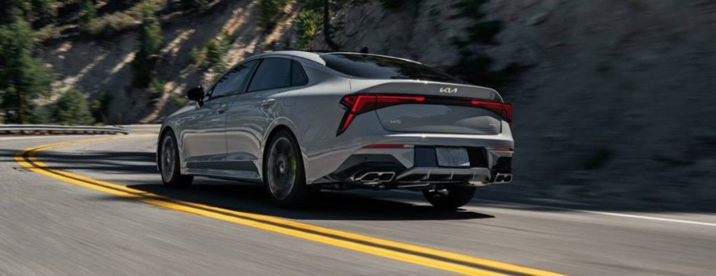 rear and side view of the 2026 Kia K5 going away on the road