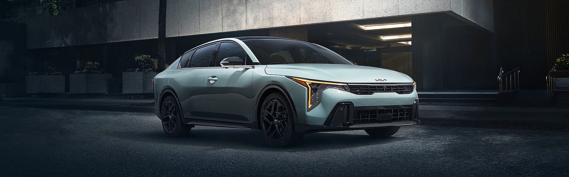 A light green Kia EV4 concept car with black wheels and a black roof is parked on a dark street at night.