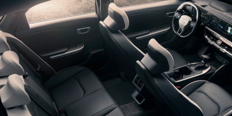 A view of a modern car's interior, showing black leather seats with light gray accents. The dashboard, steering wheel, and console are visible.