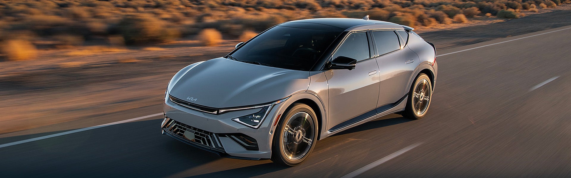 Silver Kia K4 fastback sedan driving on an open highway with a sleek, modern exterior design.