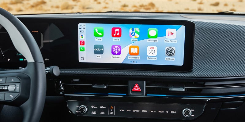 Interior of a car with a large infotainment screen showing Apple CarPlay apps, and a partial view of the steering wheel.