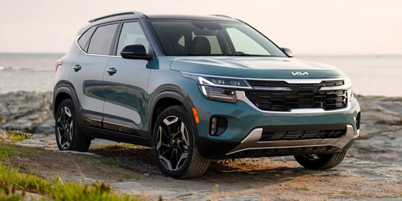 Kia Seltos parked near a rocky coastal landscape.