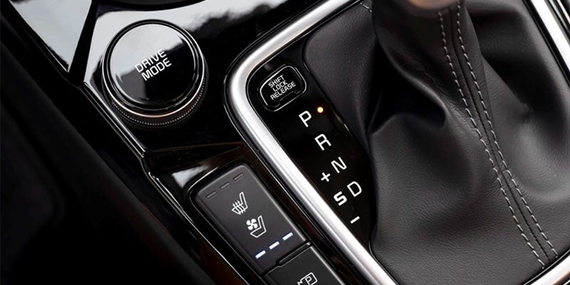 Car interior console with "Drive Mode" dial, lit "P" on the gear shift, and seat warmer/cooler buttons.