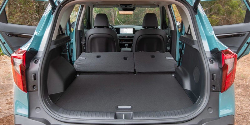 The open trunk of a teal SUV. The rear seats are folded down, extending the flat cargo space.
