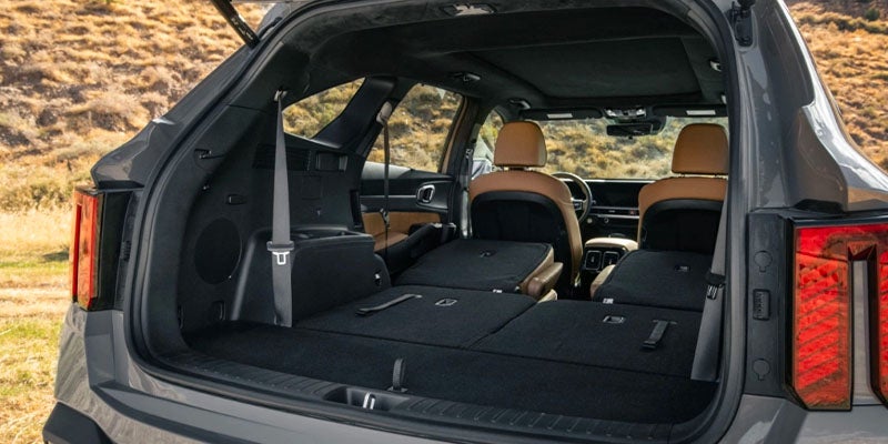 View from the open trunk of a gray SUV, showing the rear seats folded down and the front seats in tan leather.