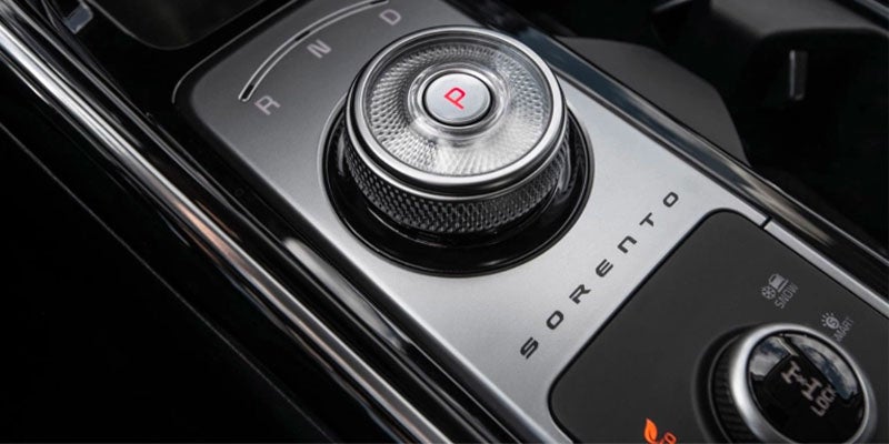 Close-up of a vehicle’s rotary gear selector and console controls.