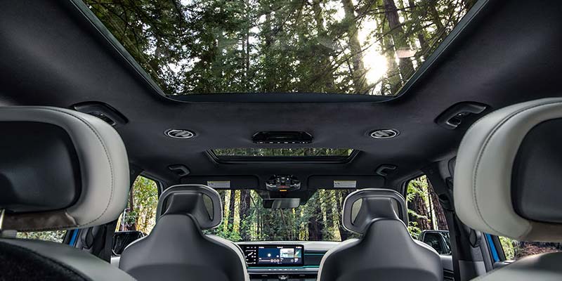 Kia EV9 interior showing panoramic sunroof and front seats.