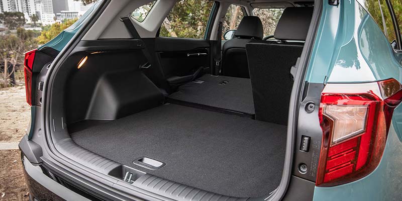 Open trunk of a teal SUV. The rear seats are folded flat, creating a large, carpeted cargo space.
